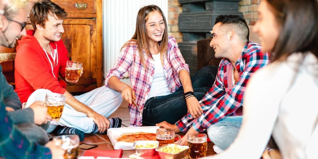 four-young-adults-sitting-on-floor-eating-pizza.jpg